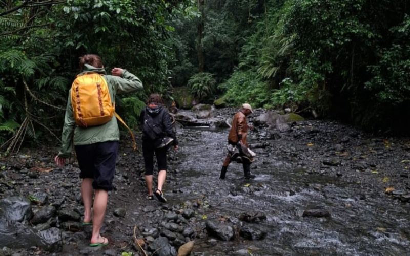 drie mensen wandelend door een rivier met weinig water